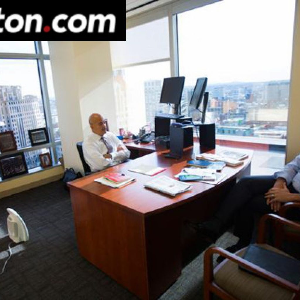 man sitting at desk in corner office