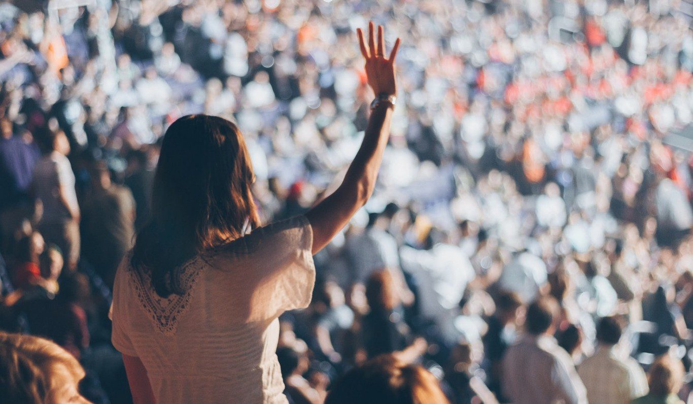 woman raising her hand in an audience