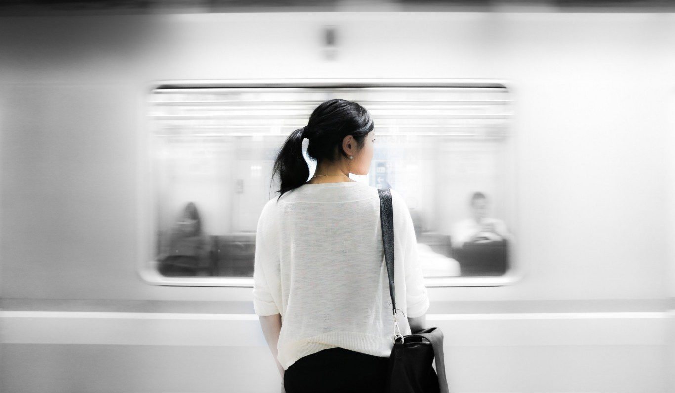 woman standing with train zooming past her