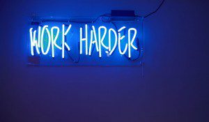 neon sign that says "work harder"