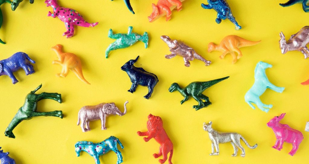 Small plastic animal shaped toys scattered across a yellow background