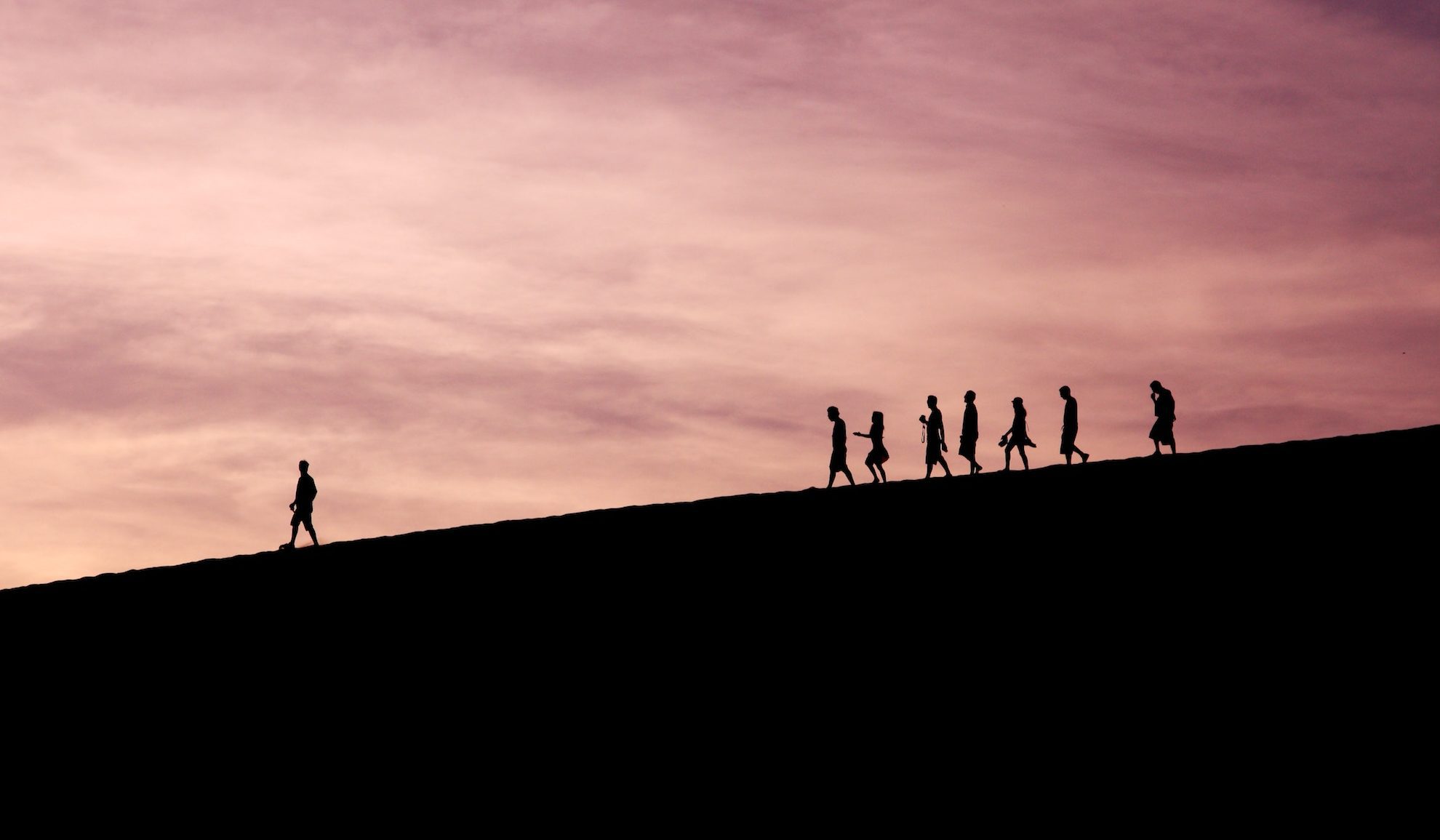 group of people in shadow walking down hill
