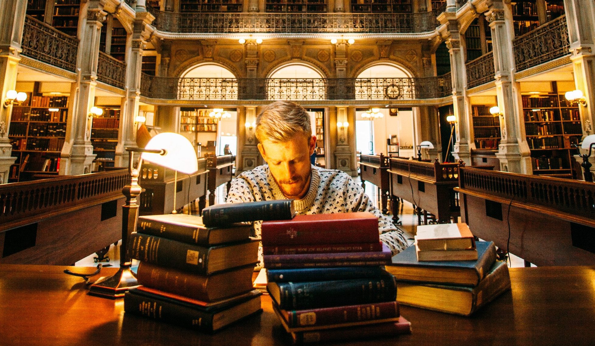 man in library with stacks of books