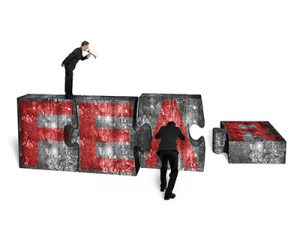 Businessman using speaker yelling at other man pushing big jigsaw puzzle concrete blocks with red FEAR word, isolated on white background