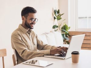 A man smiles while working at his computer at home