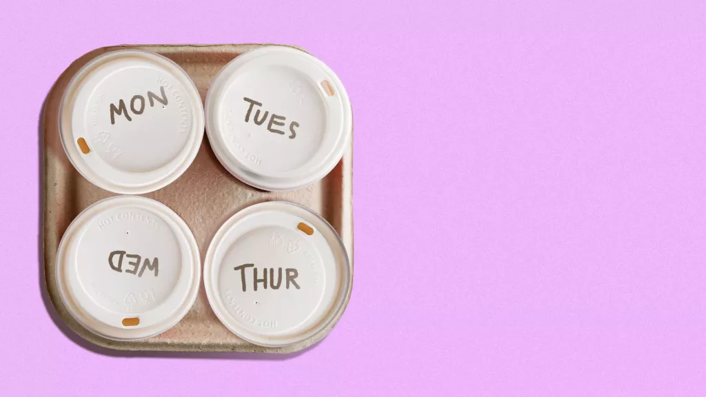 4 coffee cups together on a tray . Each is labeled with a day of the week except for Friday.