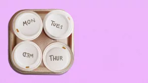 4 coffee cups together on a tray . Each is labeled with a day of the week except for Friday.