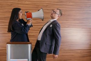 An employee demands the attention of her employer using a megaphone.