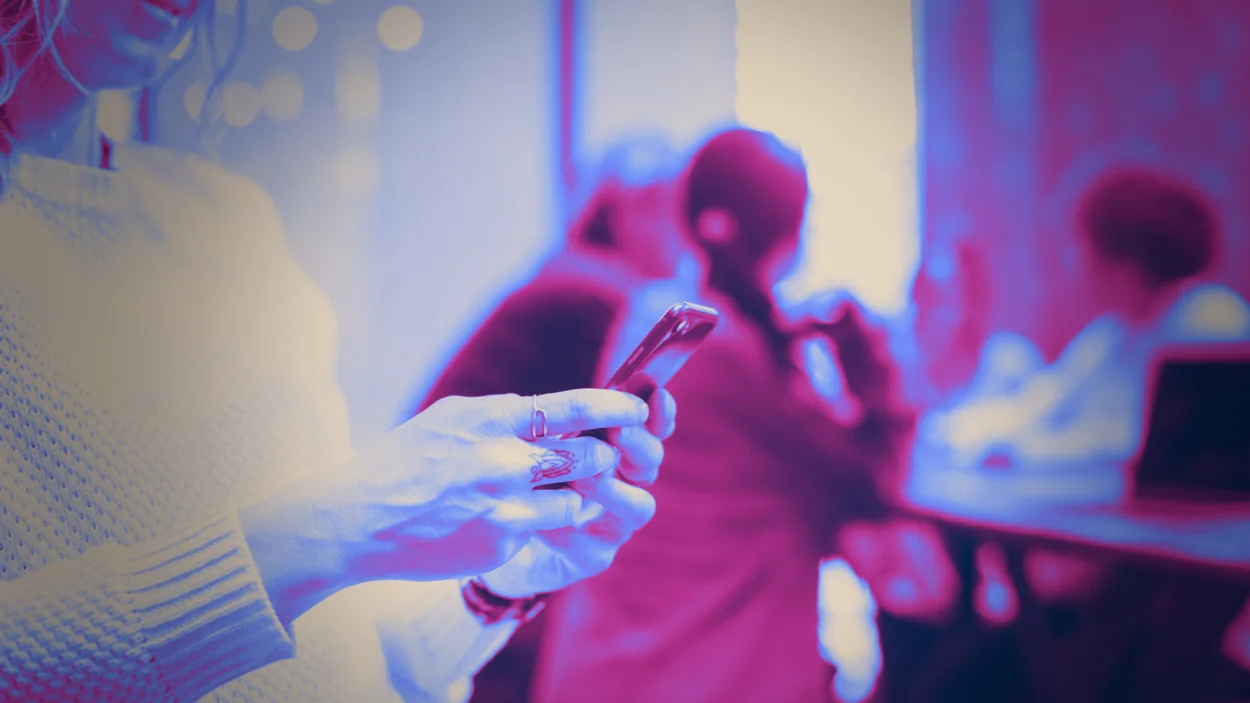 A purple tinted photo of a woman's hands using her cell phone