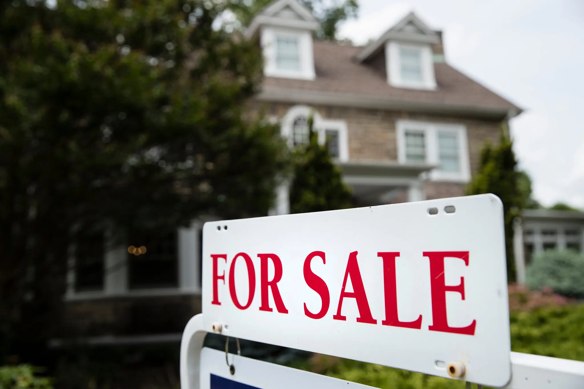 A for sale sign sits in front of a home