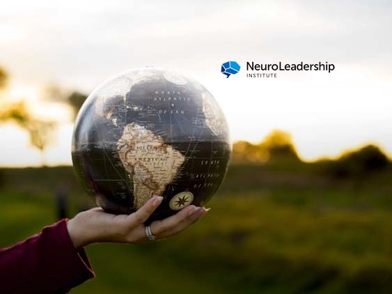 A woman's hand holds a globe in an open field. The NeuroLeadership Institute logo appears over the photo.