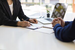A view of two people's hands positioned on a desk as they go over a resume