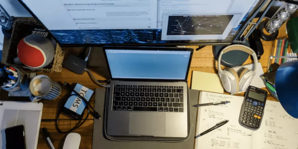 A laptop sits open on a cluttered home desk